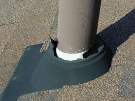 Roof vent pipe with black flashing on asphalt shingles, showing a white seal at the base