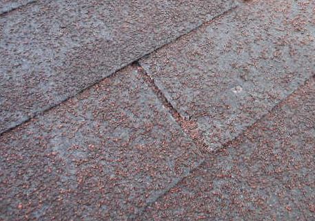 Close-up of gray and reddish-brown roof shingles with a diagonal seam.