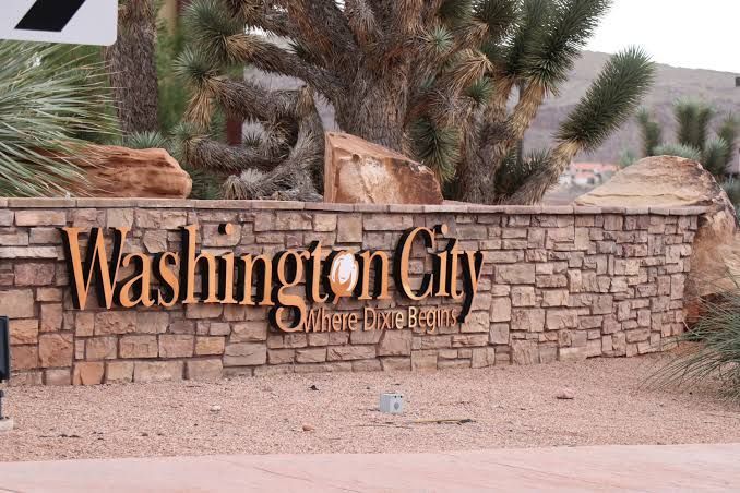Washington City stone entrance sign with palm trees and desert landscaping