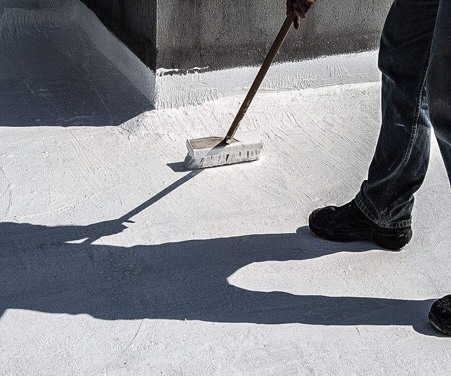 Person using a broom to sweep a white rooftop or deck in bright sunlight