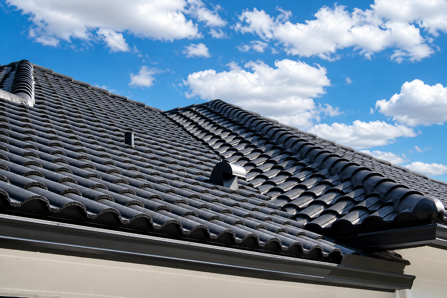 Dark gray tiled roof under a blue sky with scattered clouds