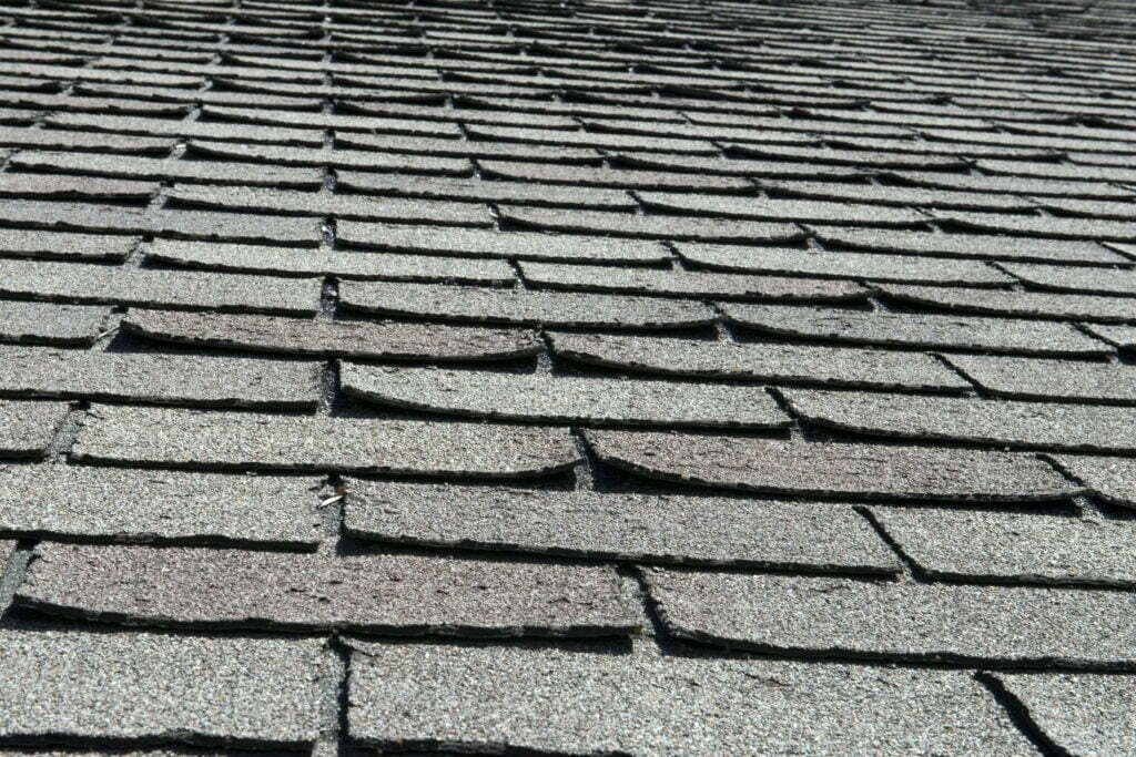 Close-up of gray roof shingles in rows, viewed from above.