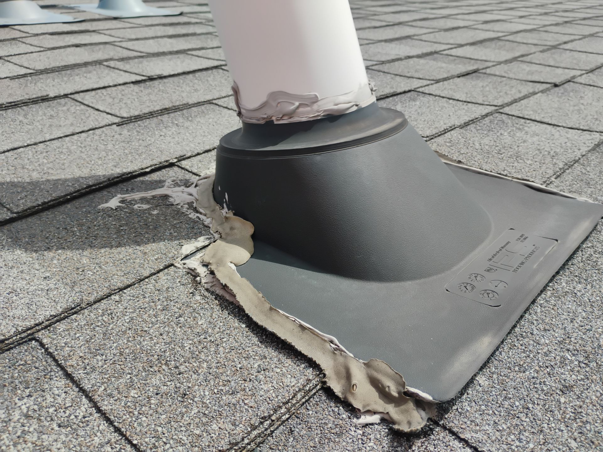 Worker using a drill to fasten red metal roofing panels on a roof