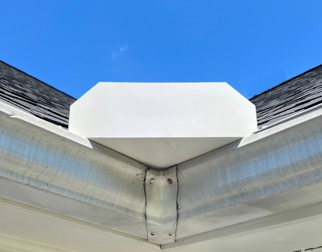 Worker applying sealant to a green corrugated metal roof while kneeling in a harness and cap