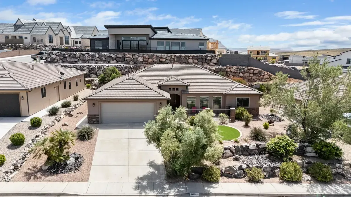 Suburban homes with desert landscaping and a driveway in the foreground under a clear sky