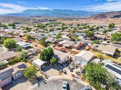 Aerial view of a suburban neighborhood with homes, trees, and mountains in the distance.