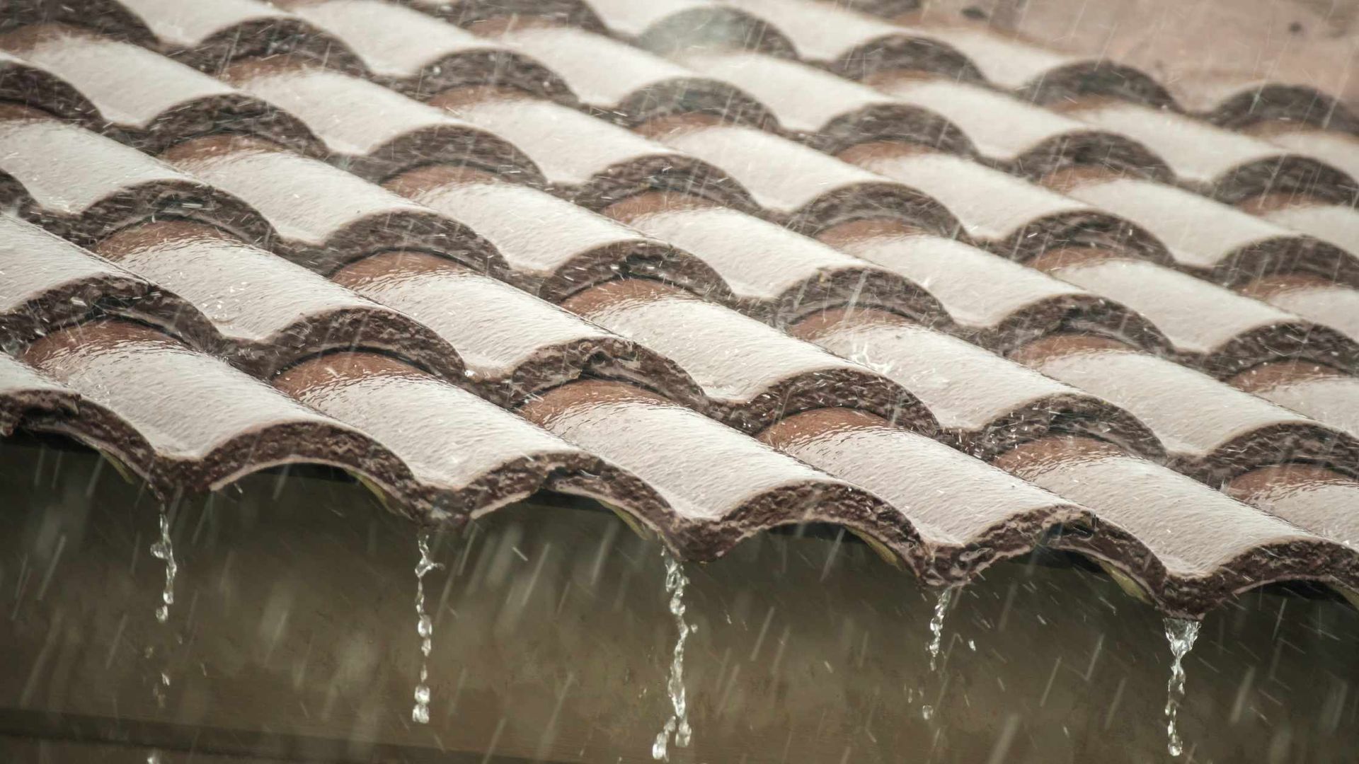 Rain dripping from a terracotta-tiled roof eave