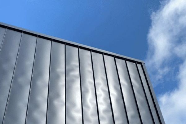 Modern glass building facade reflecting clouds against a blue sky