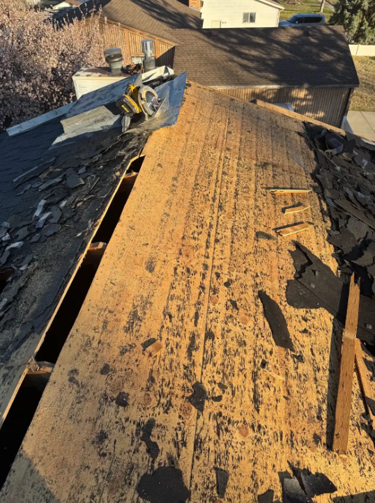 Damaged roof with a large hole and scattered debris on a sunlit building.