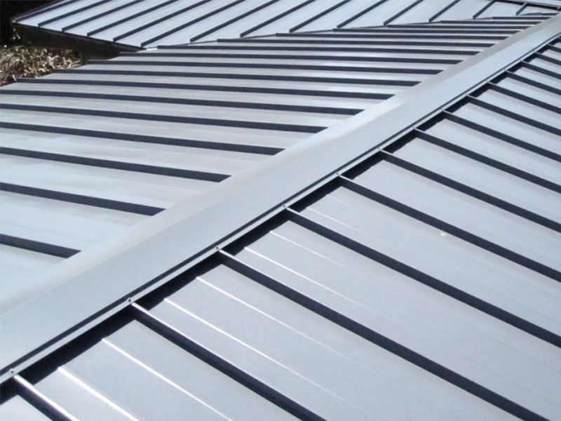 Close-up of a silver metal roof with horizontal standing seams and diagonal ridges
