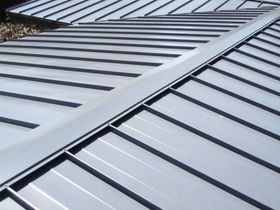 Close-up of a gray metal roof with standing seam panels and diagonal ridge lines
