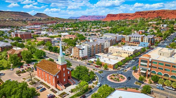 Aerial view of a downtown city with colorful buildings, a church, and mountains in the distance under a blue sky
