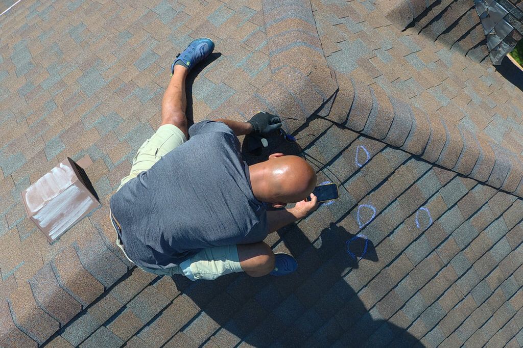 Person crouching on a brick surface, reaching toward a dark object beside a shadowed wall.
