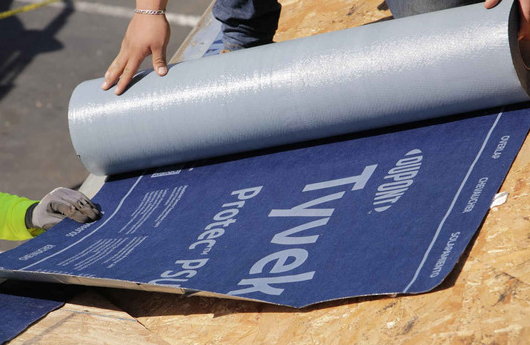 Close-up of red metal roofing panels with overlapping seams and a ridge intersection