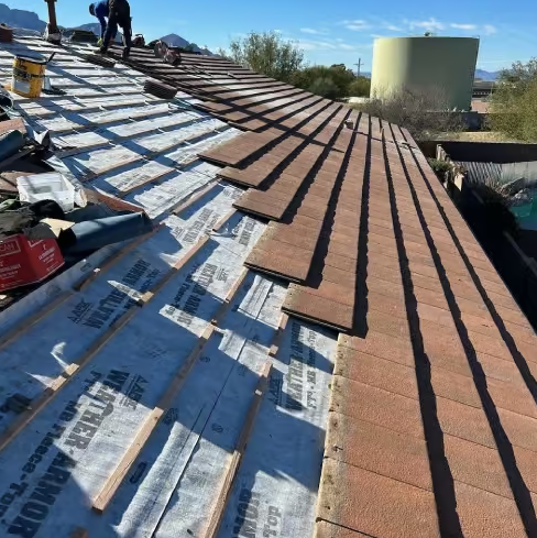 Tile roof underlayment replacement in progress during a re-felt in St. George, Utah, with tiles lifted and new synthetic underlayment exposed
