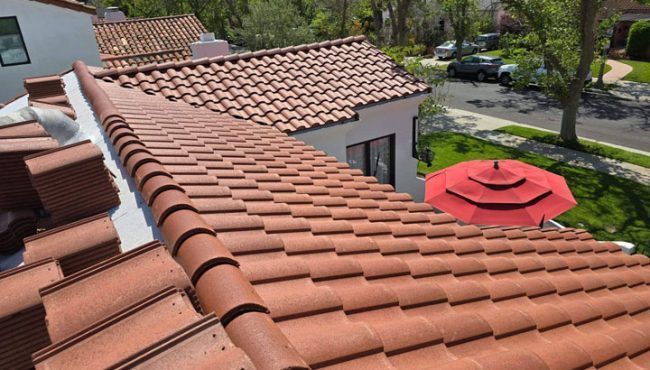 Tiled roof with red clay shingles overlooking a suburban street and a red patio umbrella in the yard