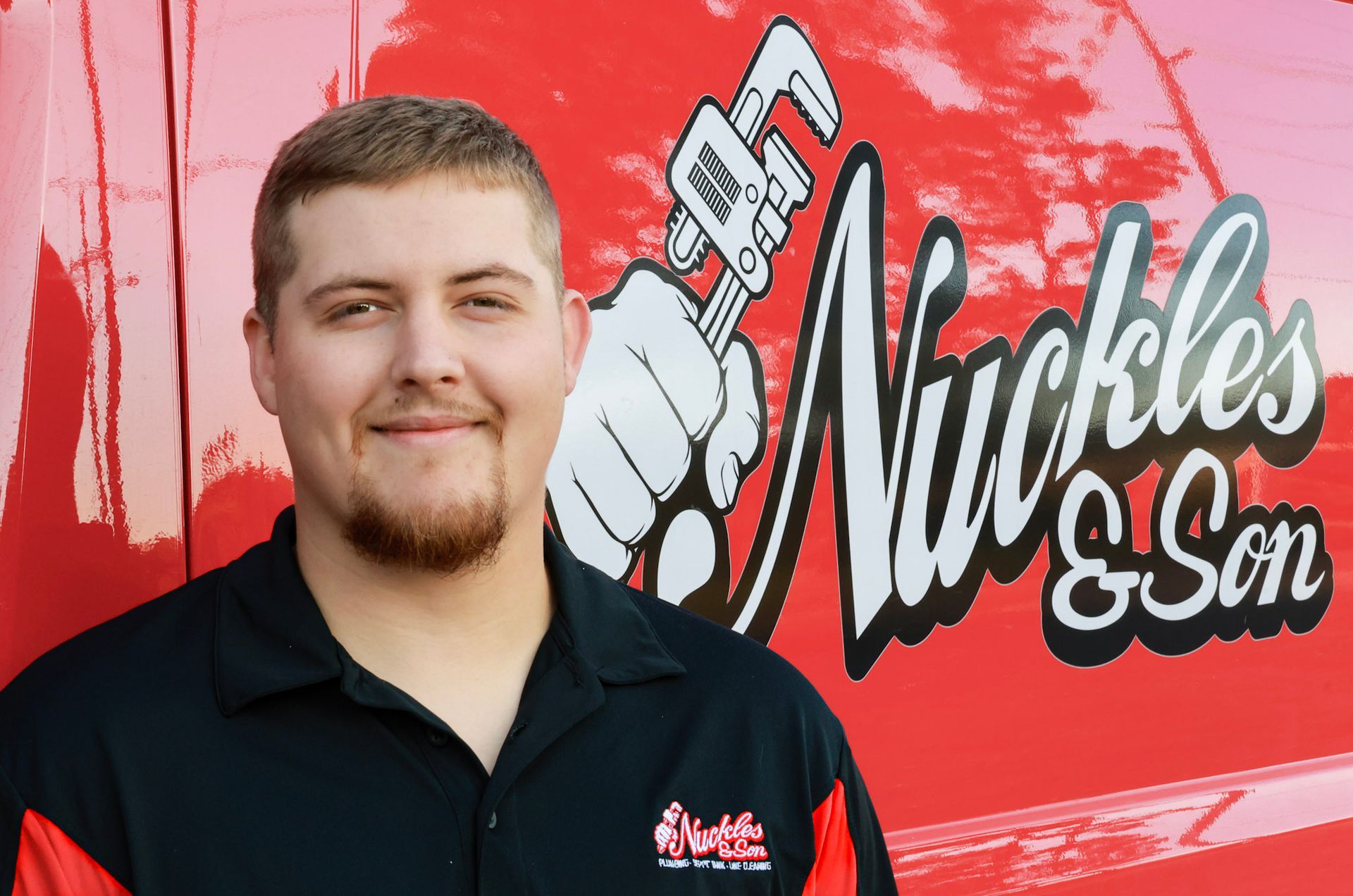 Man standing in front of a red truck with the Nickles & Son logo, wearing a black polo shirt.