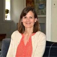 A woman is sitting on a couch in a living room.