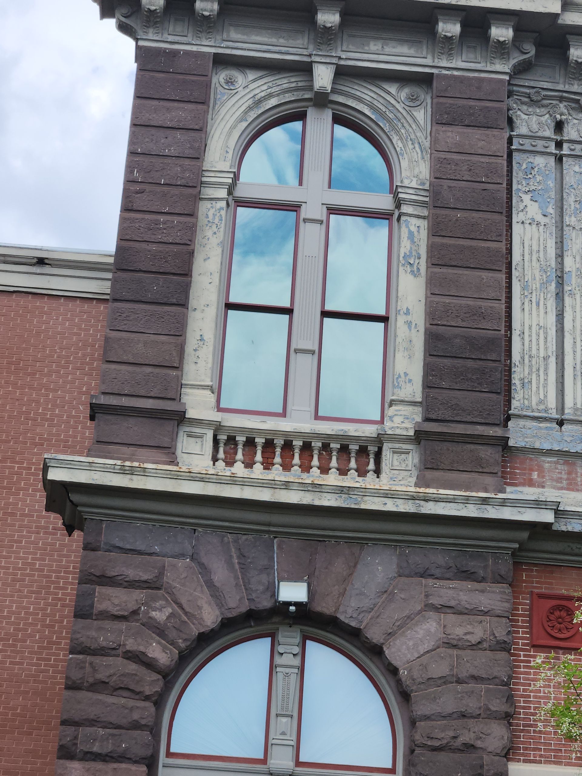 Dark brick building facade with arched windows and a red-tiled roofline