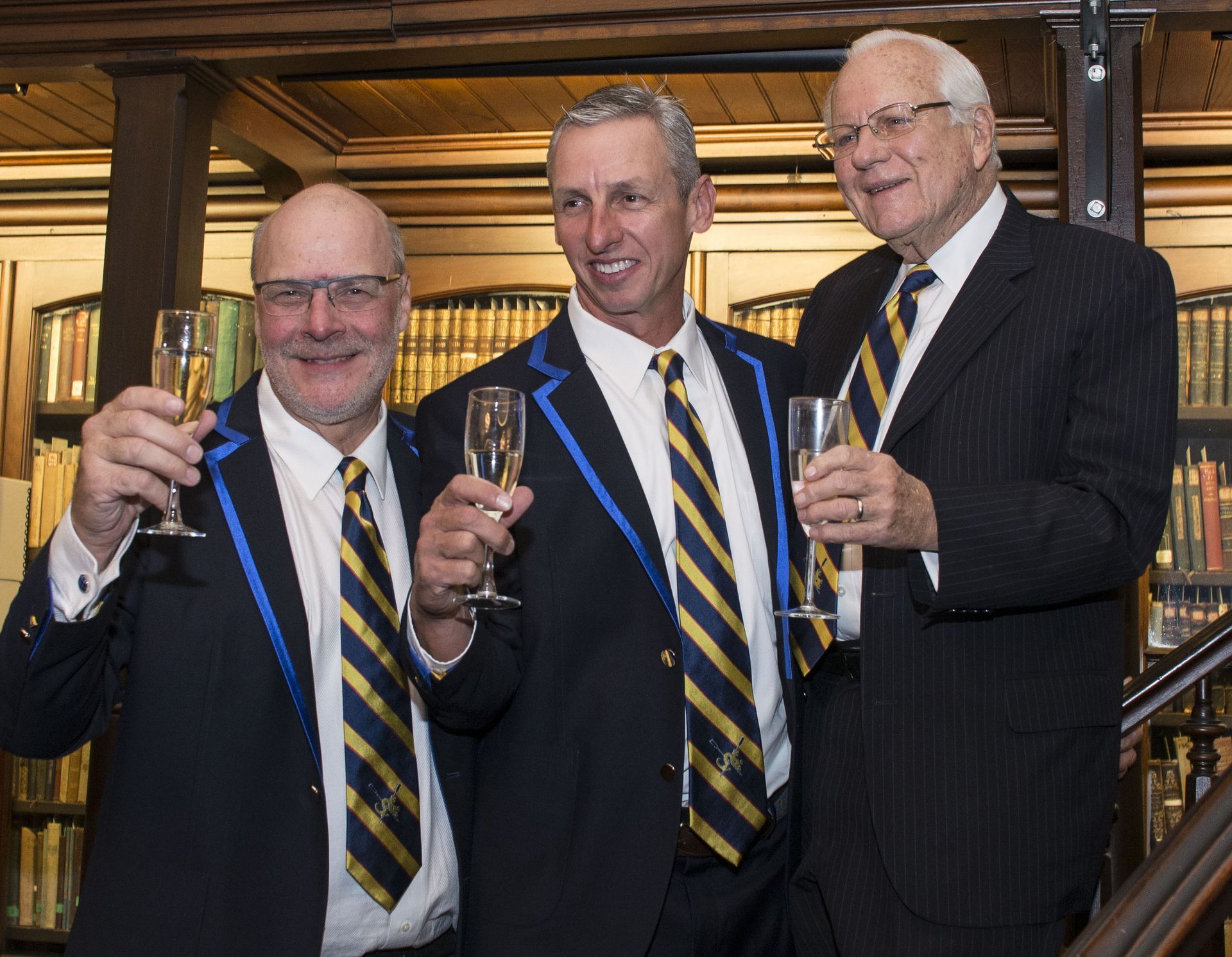 Three men in suits holding champagne glasses at a formal indoor event