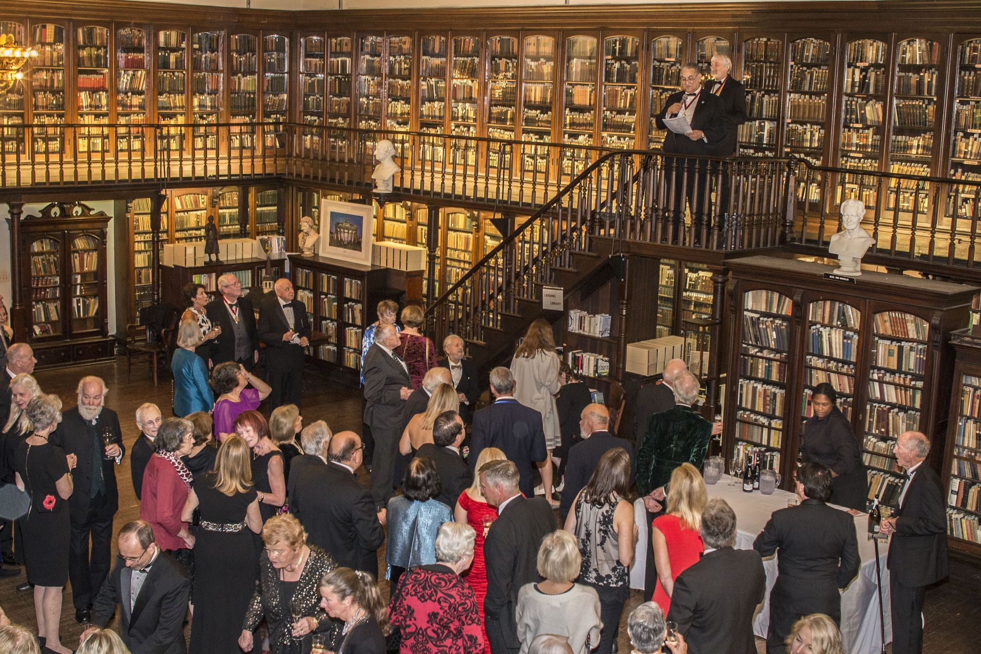 Crowded bookstore interior with shelves of books and people browsing, seen from a balcony stairs view