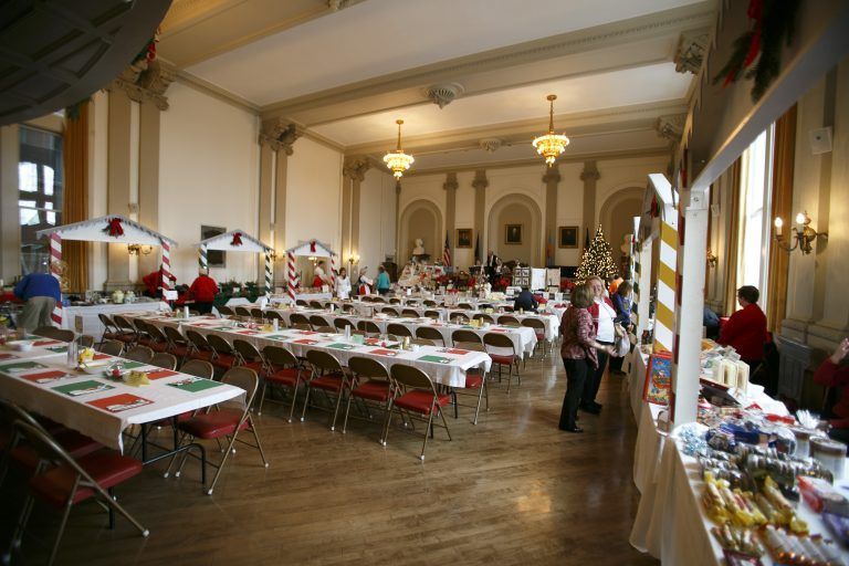Banquet hall with rows of white-covered tables and red chairs set up for an event