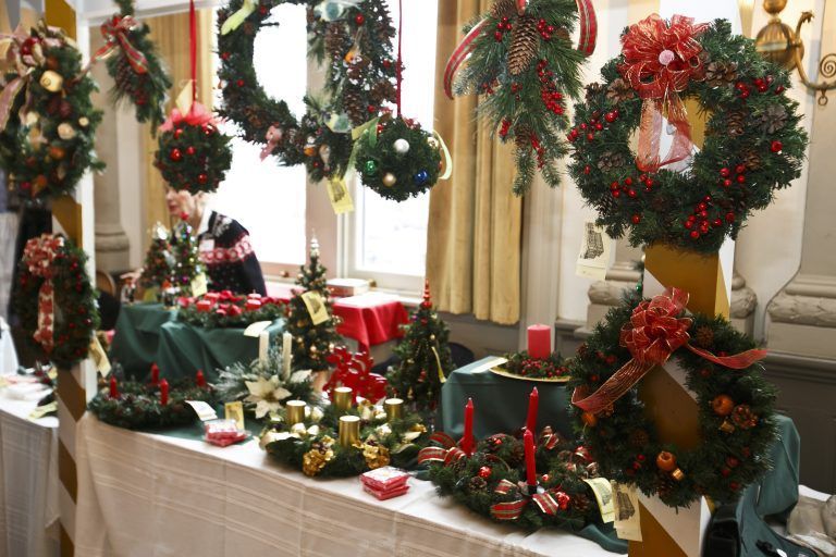 Holiday table display with Christmas wreaths, garlands, red candles, and festive decorations