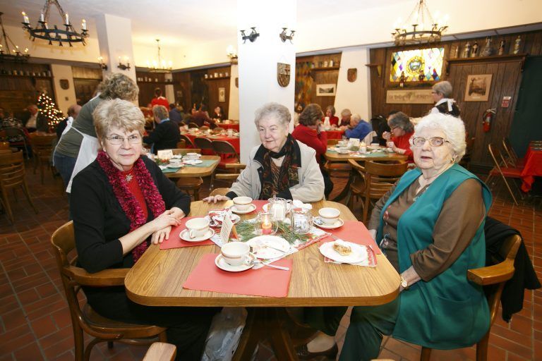 Three people seated at a restaurant table with tea cups and plates in a cozy dining room