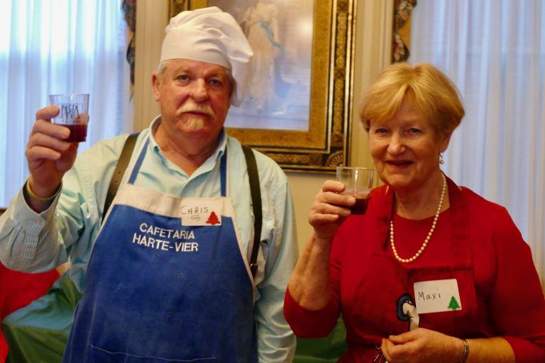 Two people in costumes raise drinks at a festive indoor gathering.