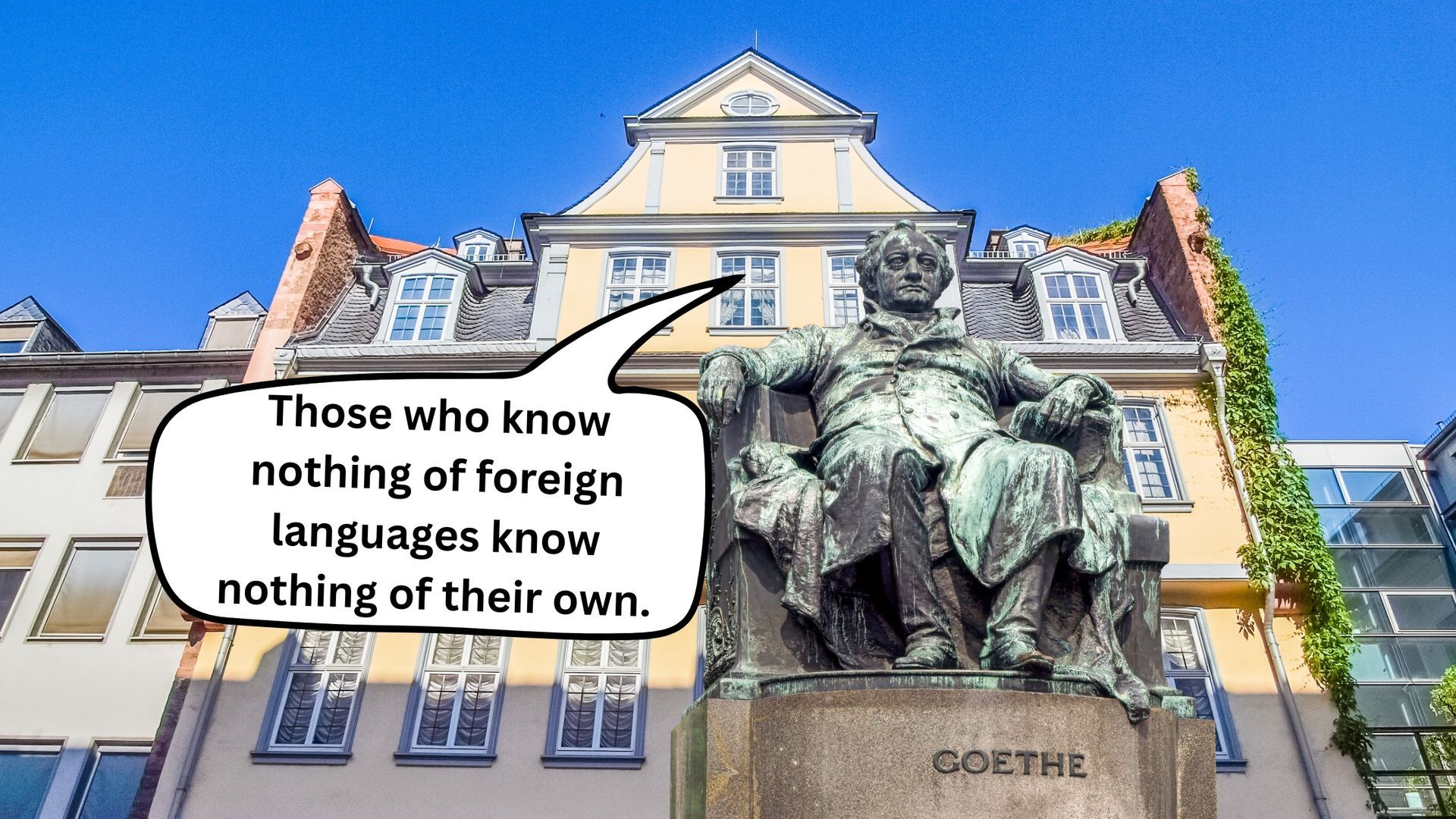 Statue in front of European buildings with quote about knowing foreign languages and their own.