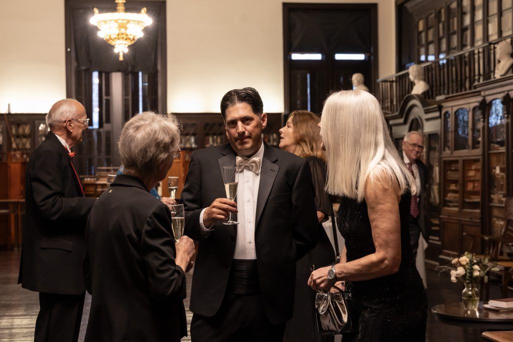 People mingling and holding drinks in a warmly lit, elegant bar or lounge