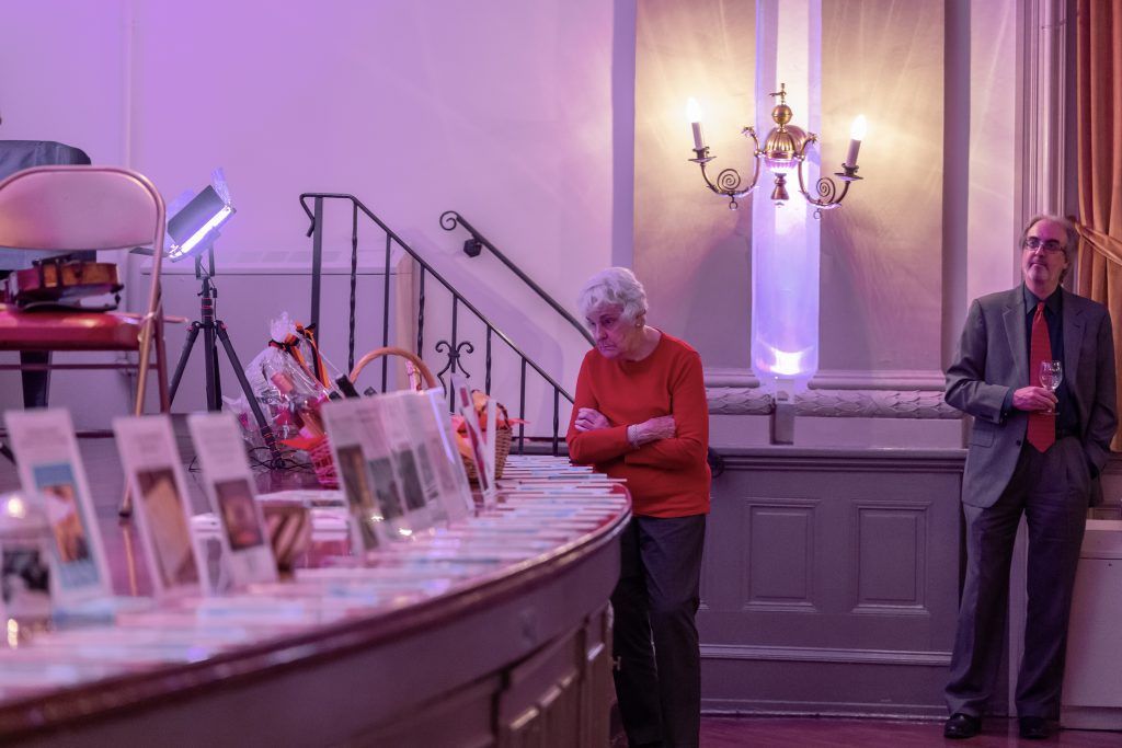 Dessert table at a softly lit event, with framed photos and two people standing nearby.