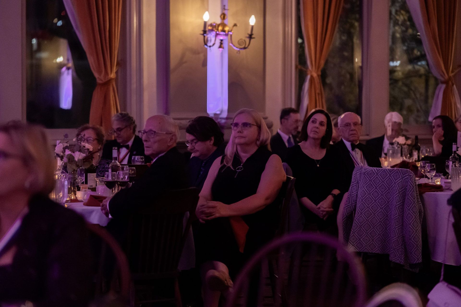 Guests seated at tables in a warmly lit banquet hall with purple lighting