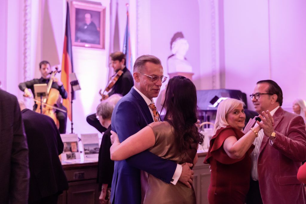 People dancing at a formal indoor event, with live musicians performing in the background.
