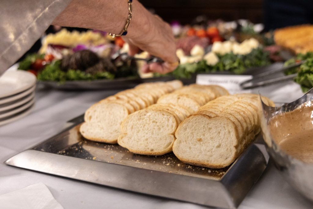 Tray of sliced bread on a buffet table with salad dishes in the background