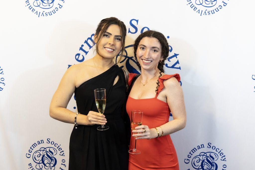 Two women posing with awards in front of a white event backdrop.