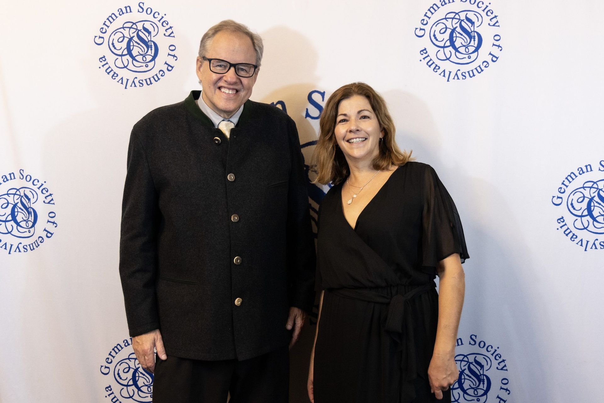 Two smiling people pose in front of a Step Up backdrop at an event