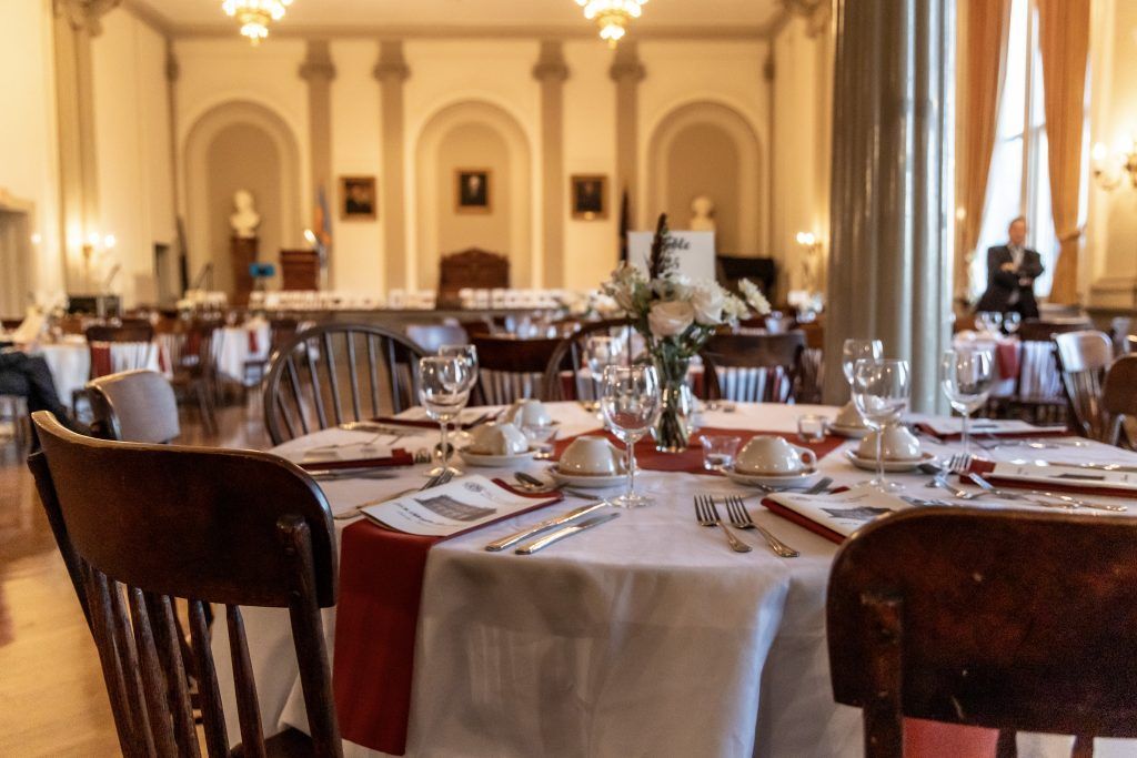 Elegant dining room with set tables, white tablecloths, and warm chandeliers in a historic interior