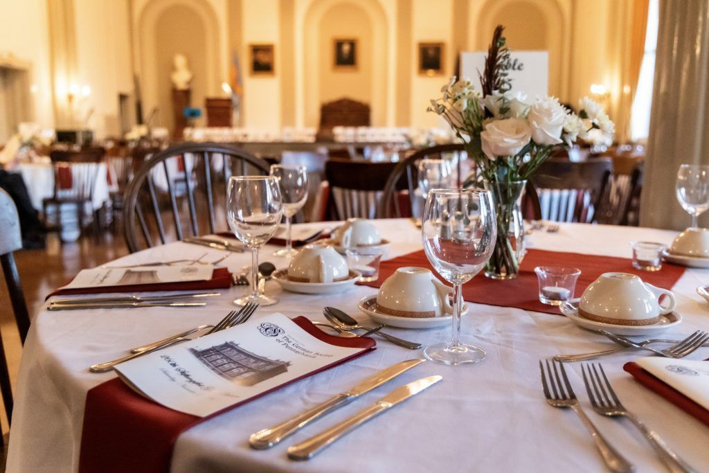Elegant restaurant table set with white linens, wine glasses, gold utensils, and white floral centerpieces