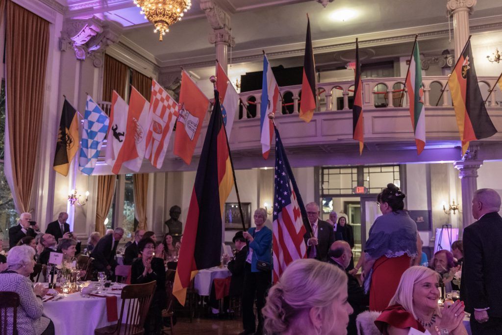 People seated at a banquet hall with many national flags and purple lighting