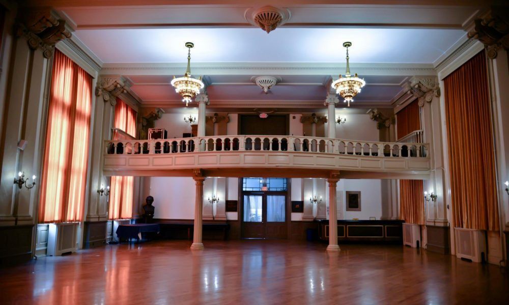 A large empty room with a balcony and a piano.