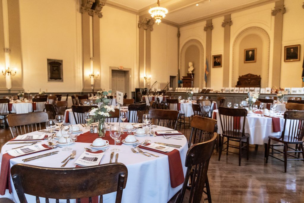 Elegant banquet hall with round tables, white tablecloths, and wooden chairs set for an event