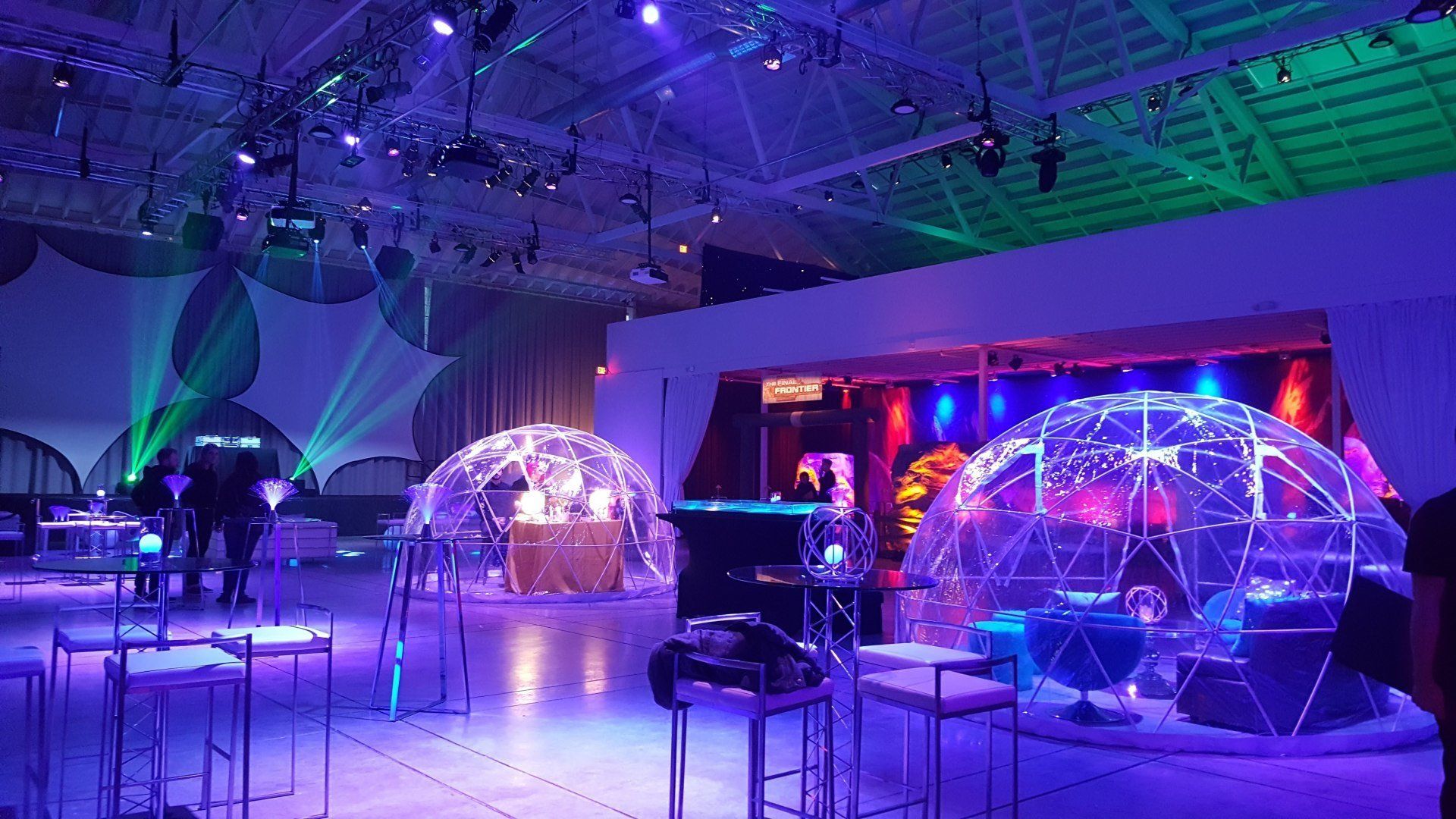 Event space with igloo-like structures, lit with blue and green lights. People in the background.