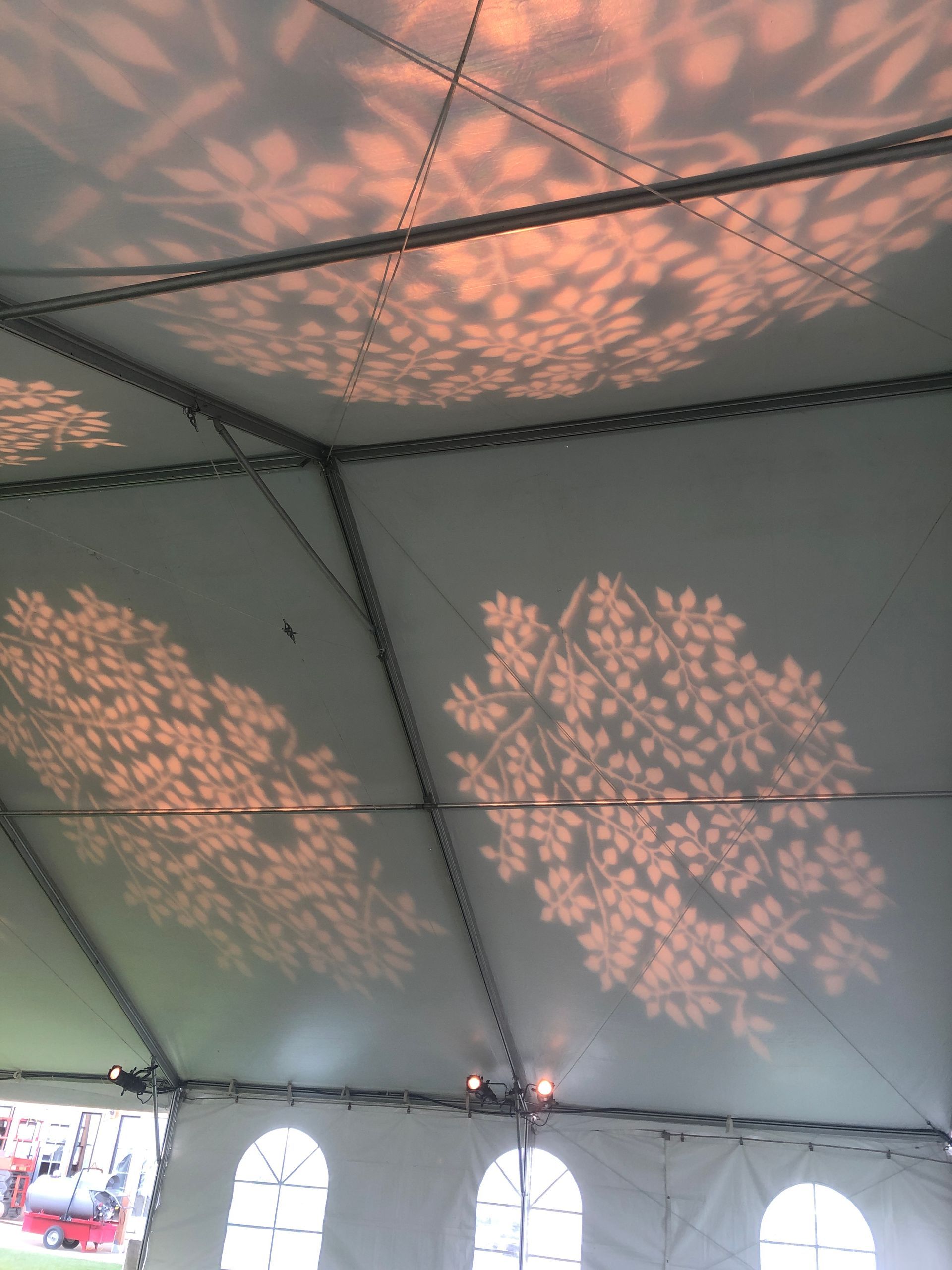 Tent ceiling with projected leaf patterns in warm light.