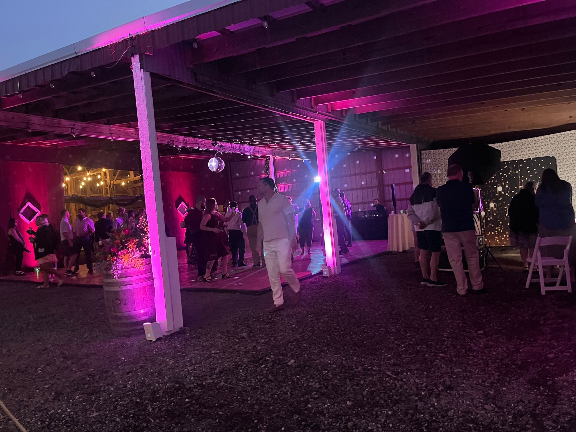 Party under a covered structure with pink and blue lights. People are dancing and socializing.