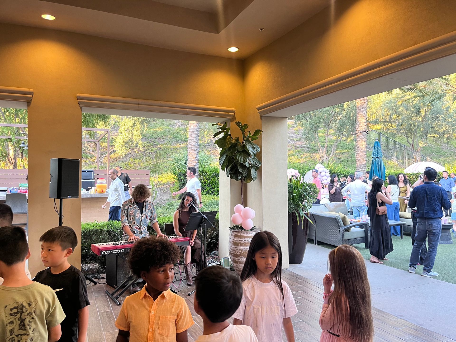 People at outdoor party; band playing keyboard. Children watching.