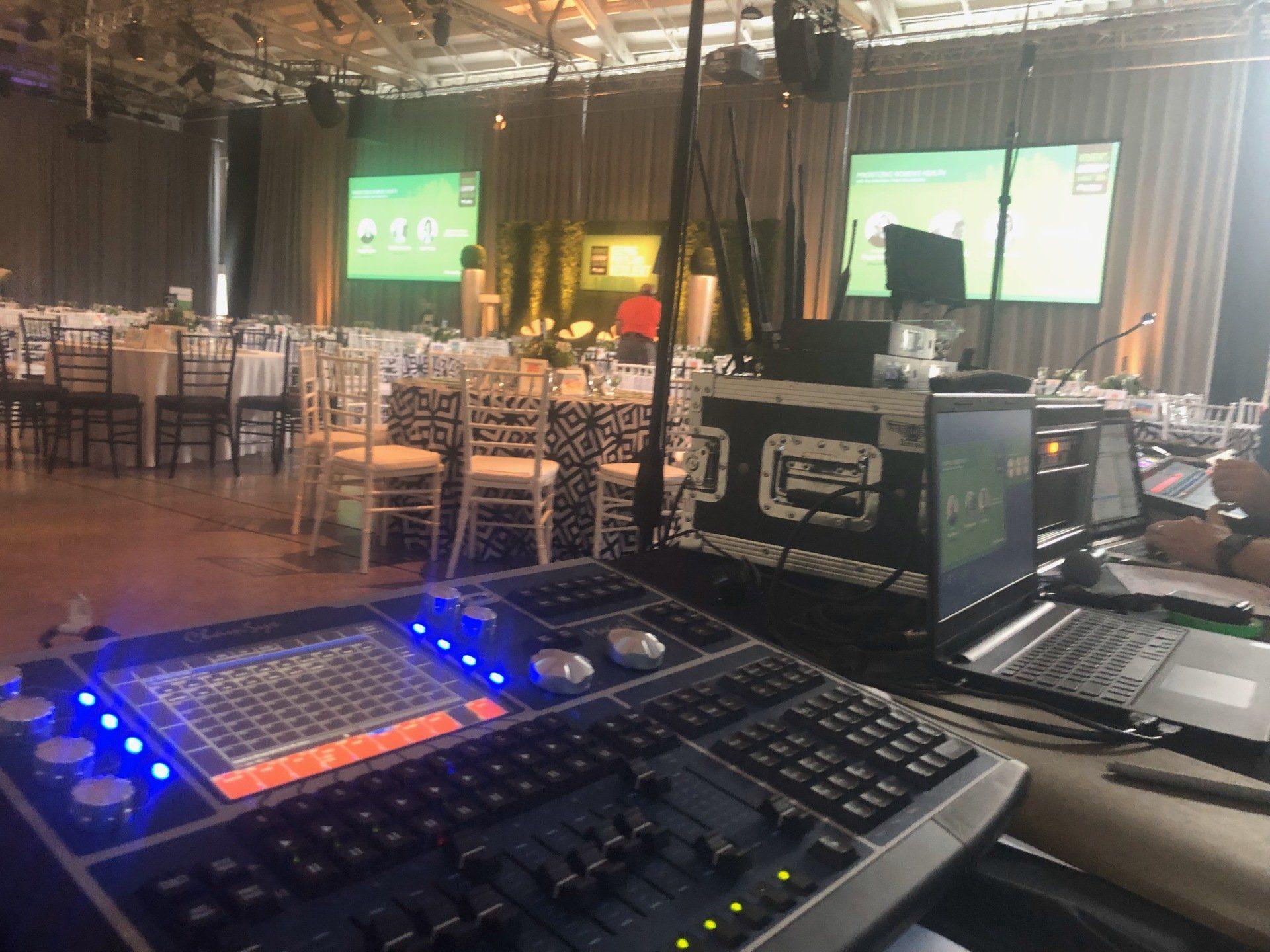 Control board in foreground, event setup in background, screens displaying content.