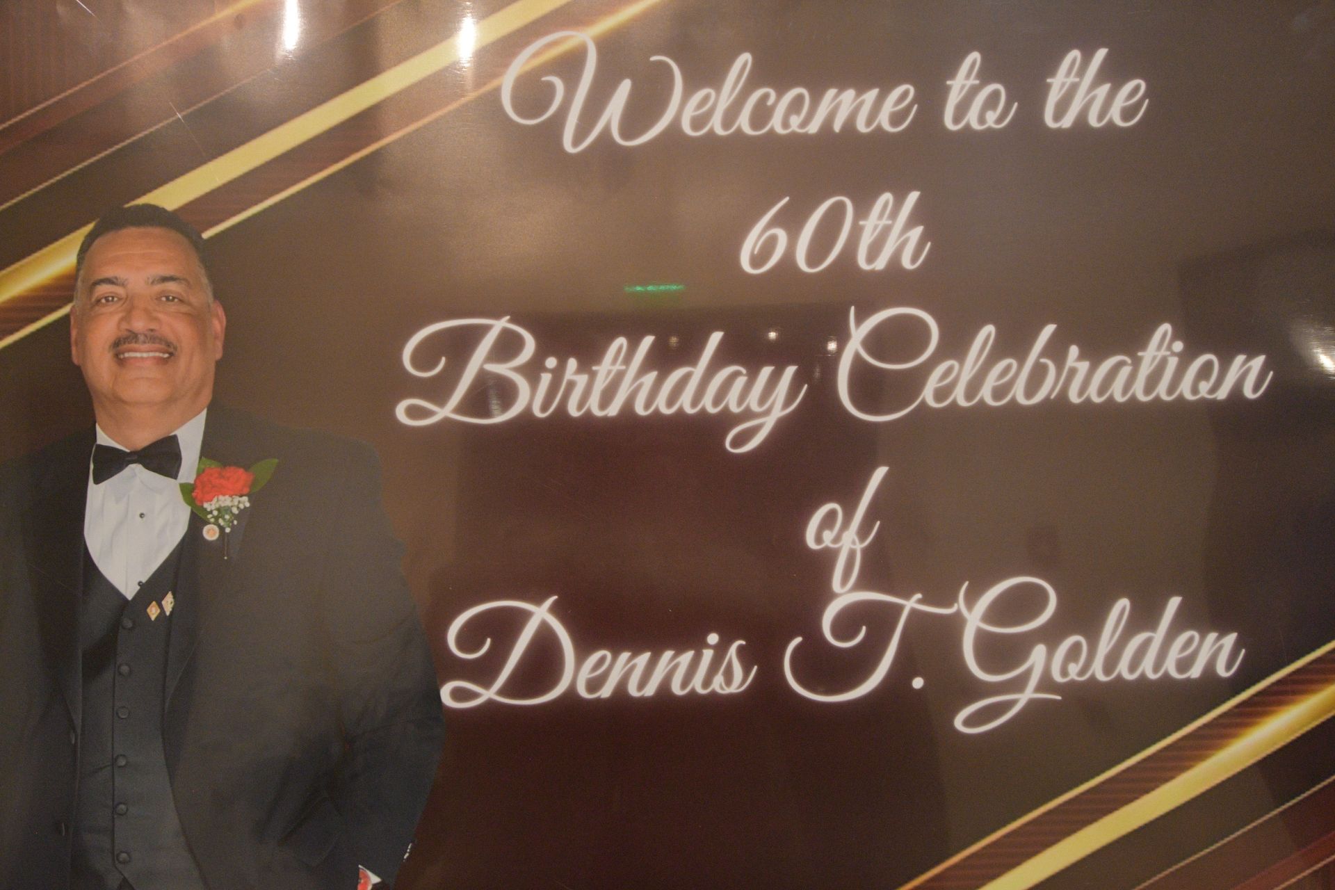 Man in tuxedo smiles at his 60th birthday celebration sign: 
