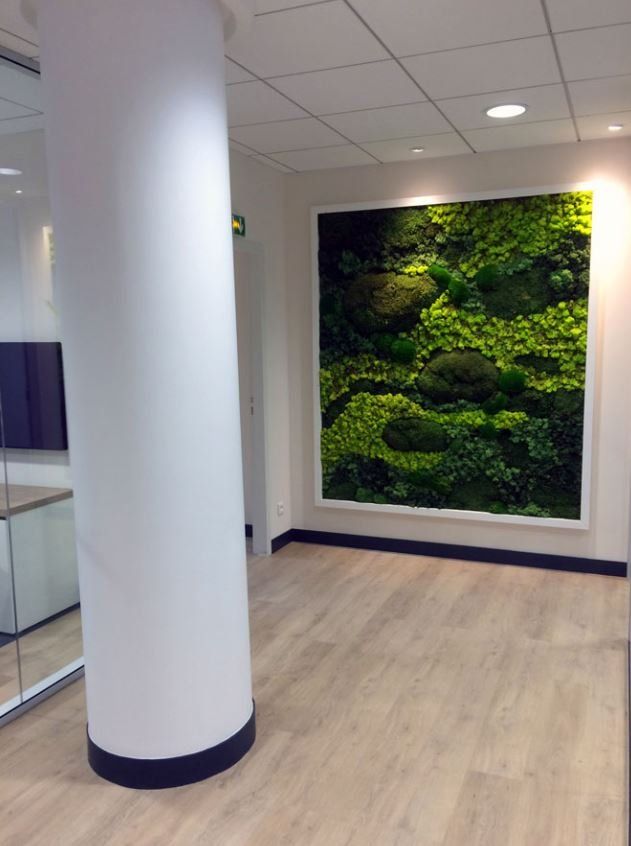 Hallway with a large moss wall art piece framed in white; a white column is in the foreground.