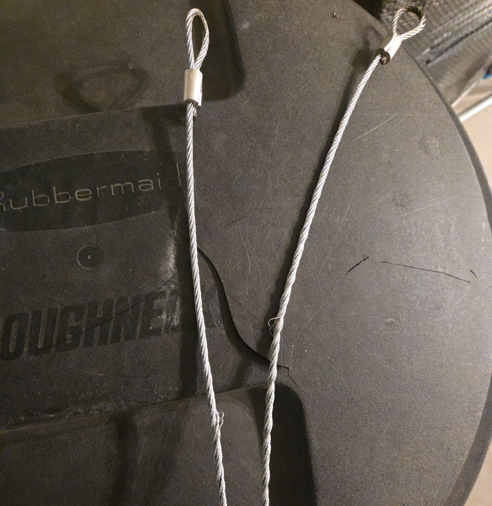 Black rubber mat with two metal loops and cords on a dark surface
